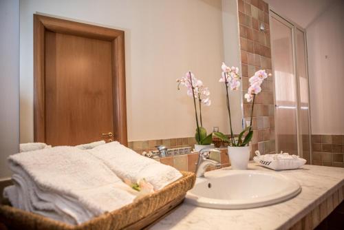 La salle de bains est pourvue d'un lavabo, d'un miroir et de fleurs. dans l'établissement Palazzo Cosentino, à Caltanissetta