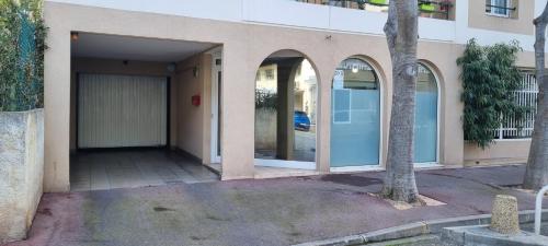 a building with two large glass doors and a tree at Le Cap St-Charles - Spacieux dernier étage - terrasses - climatisation - parking in Juan-les-Pins