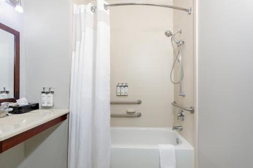 een witte badkamer met een douche en een wastafel bij Holiday Inn Express Hotel & Suites Jacksonville - Mayport / Beach, an IHG Hotel in Jacksonville