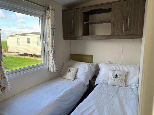 two beds in a small room with a window at D34 Steeple Bay Caravan Site in Chelmsford