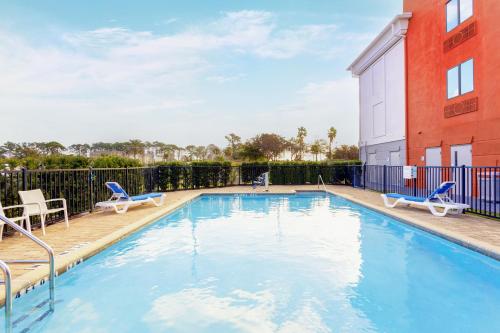 a swimming pool with chairs and a building at Holiday Inn Express Hotel & Suites Jacksonville - Mayport / Beach, an IHG Hotel in Jacksonville