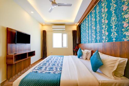a bedroom with a large bed and a tv at Roseewood Hotel Near Delhi International Airport in New Delhi