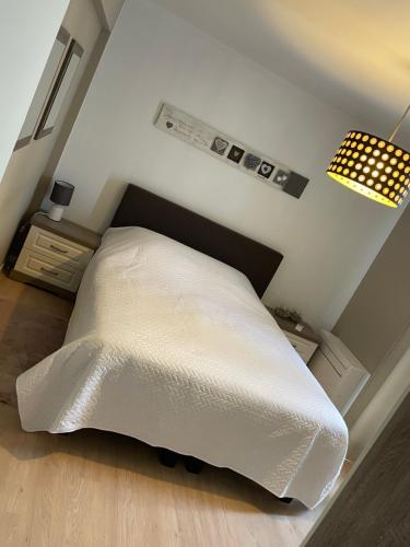 a white bed in a bedroom with a lamp at Appartement Anthony in Blankenberge
