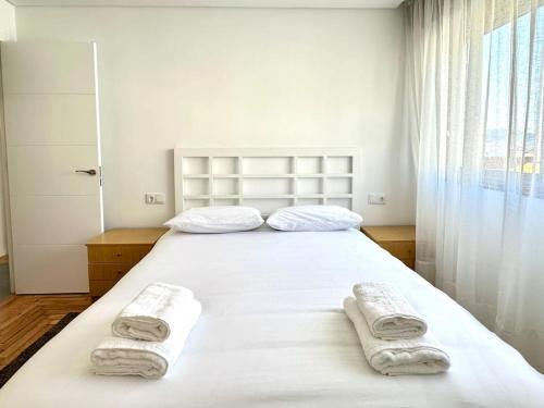 1 dormitorio con 1 cama blanca grande y toallas. en Apartamento Boutique Centro en Vigo