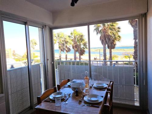 a dining room table with a view of the beach at Logis des Palmiers YourHostHelper in Gruissan