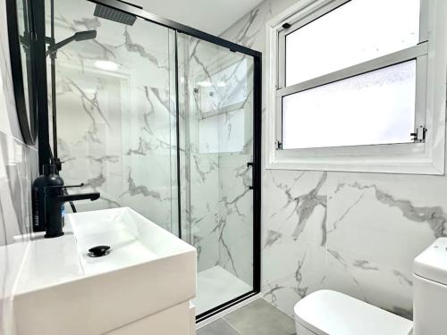 y baño blanco con lavabo y ducha. en Apartamento Boutique Centro, en Vigo