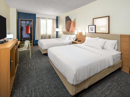 a hotel room with two beds and a desk at Spark by Hilton Savannah Airport in Savannah