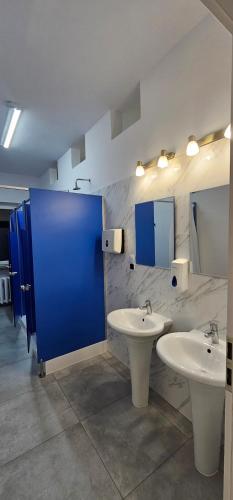 ein Badezimmer mit zwei Waschbecken und einer blauen Tür in der Unterkunft Rest Hostel Airport Modlin in Nowy Dwór Mazowiecki
