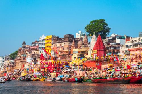 a group of boats in the water in front of buildings at Golden Lotus Varanasi in Varanasi