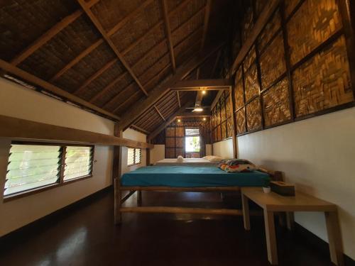 een slaapkamer met een bed in een kamer met houten plafonds bij Coleto Siargao in San Isidro