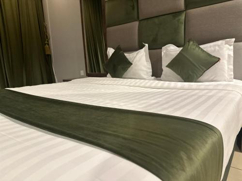a large bed with white sheets and green pillows at بوابة الورود للشقق المخدومة - فئة اقتصادي in Taif
