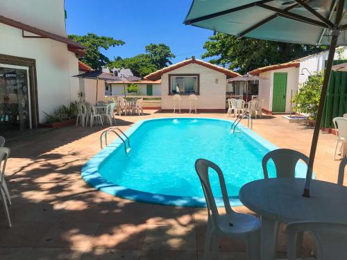 a swimming pool with a table and chairs and an umbrella at pousada da sarafina ltda in Salvador