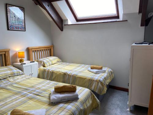1 Schlafzimmer mit 2 Betten und einem Fenster in der Unterkunft Foxglove Barn in South Brent