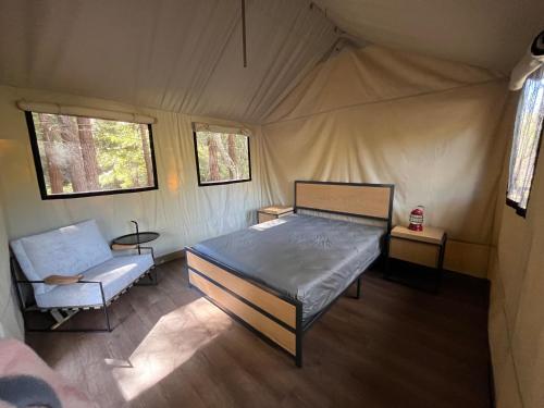 The Camp at Carmel Valley في وادي كارمل: غرفة نوم بسرير وكرسي في خيمة