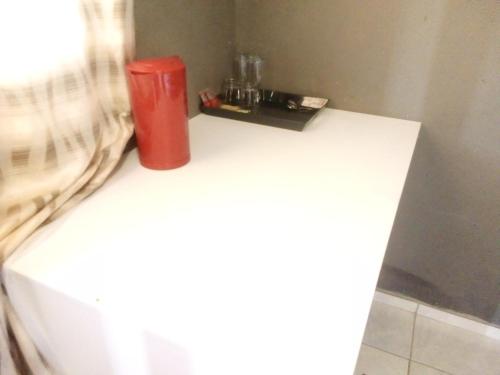 a red trash can sitting on top of a white table at Letz Guest Lodge in Tolwe