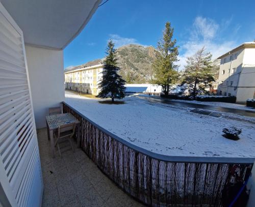 un balcón con un patio cubierto de nieve con un árbol. en Apartamento CREMALLERA Ribes de Freser, en Ribes de Freser