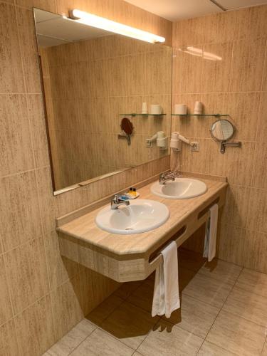 un bagno con due lavandini e un grande specchio di Hotel Barreiro a Leira