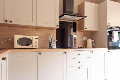 cocina con armarios blancos y microondas en Grove House en North Queensferry