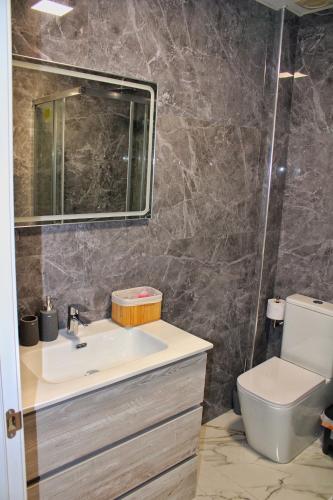 a bathroom with a sink and a toilet and a mirror at Calpe apartamento nuevo 1a línea playa piscina in Calpe