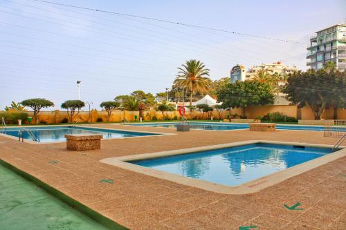 una piscina en un complejo con árboles y edificios en Calpe apartamento nuevo 1a línea playa piscina, en Calpe