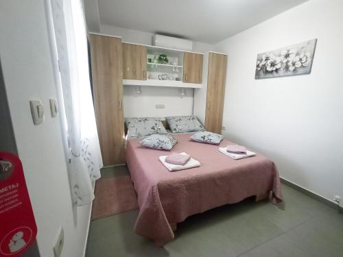a small bedroom with a pink bed with two pillows at Soba Ulika in Motovun