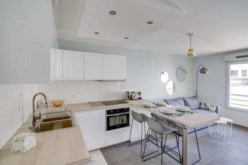 une cuisine avec des armoires blanches et une table avec des chaises dans l'établissement Le galet, appartement de standing, hyper centre, parking privé, à 100 m de la mer, à Antibes