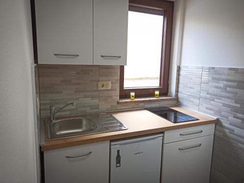 eine Küche mit weißen Schränken, einem Waschbecken und einem Fenster in der Unterkunft Soba Ulika in Motovun
