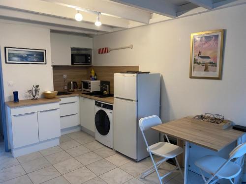 a kitchen with a refrigerator and a table with chairs at Appartement Duplex, Résidence Victoria, à 2min de la Grande Plage in Quiberon