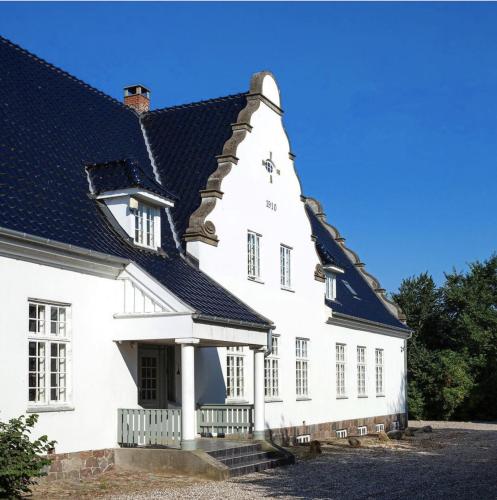 ein weißes Haus mit schwarzem Dach in der Unterkunft Jungshovedgaard Bed & Breakfast in Præstø