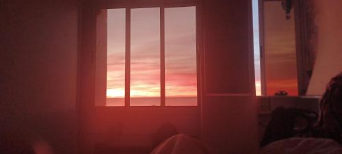 una ventana en una habitación con puesta de sol en Hergla Sea view apartment & room en Harqalah