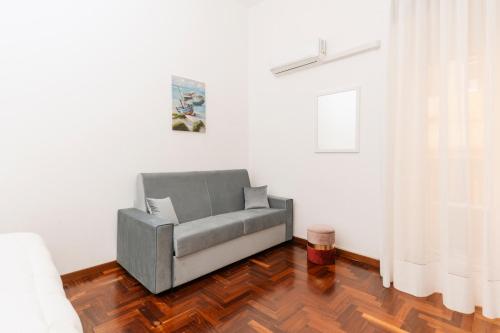 a grey couch in a white room with a wooden floor at Piazza Tasso Suite in Sorrento
