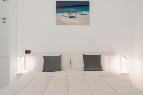- un lit blanc avec des oreillers gris et une photo sur le mur dans l'établissement Piazza Tasso Suite, à Sorrente