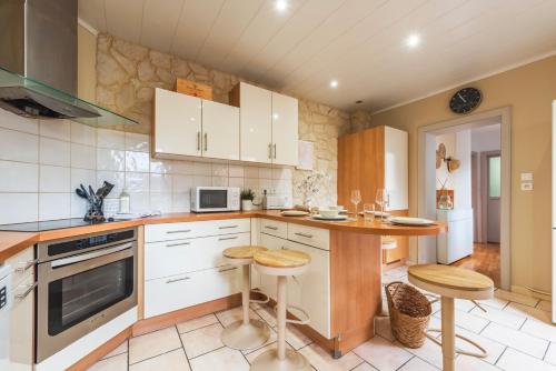 une cuisine avec des placards blancs, une table et des tabourets dans l'établissement Nouveau - Faubourg National - En face de la Gare, à Strasbourg