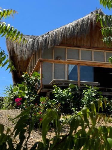 a house with a thatched roof and some flowers at La Cabaña de Iza in Canoas