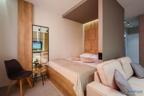 a bedroom with a bed and a chair and a mirror at Seafront Residence Makarska in Makarska