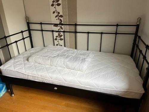 a bed with a black frame and white sheets at Monteurzimmer am Holzbach in Maroth