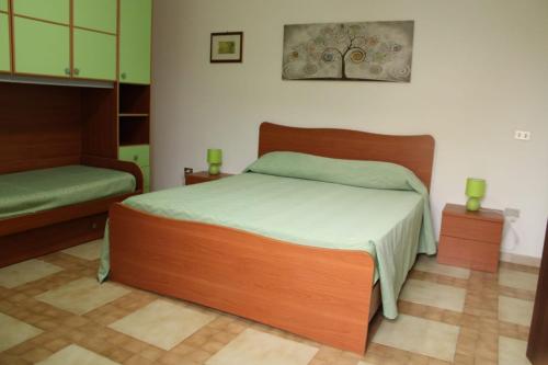 a bedroom with a large wooden bed with green sheets at B&B La Petite Maison in Santa Domenica