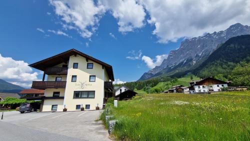 Ein Gebäude auf einem Feld mit Bergen im Hintergrund in der Unterkunft Tiroler Alpblick Appartements in Ehrwald