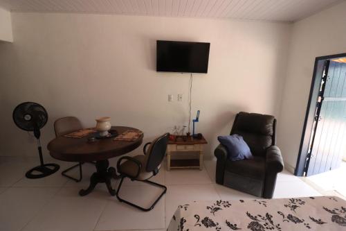 a living room with a table and a tv on the wall at Estalagem do Rancho in Miguel Pereira