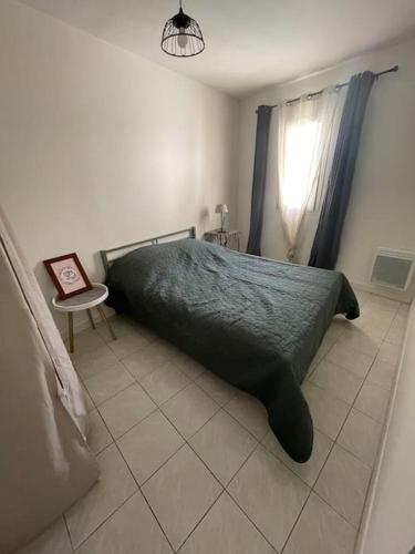 une chambre avec un lit, une table et une fenêtre dans l'établissement Charmant appartement, à Saint-Thibéry