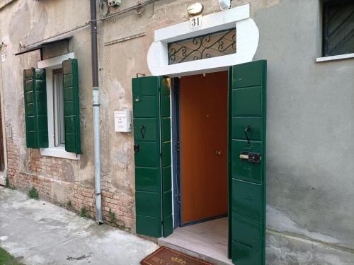 una puerta abierta a un edificio con persianas verdes en L'approdo en Venecia