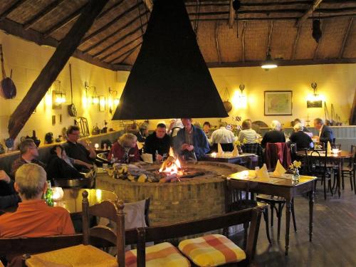 a group of people sitting around a fire in a restaurant at De Koevoet in Teroele