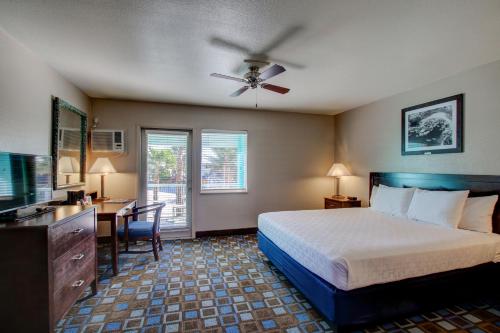 Dormitorio con cama, escritorio y TV en The Nautical Beachfront Resort, en Lake Havasu City
