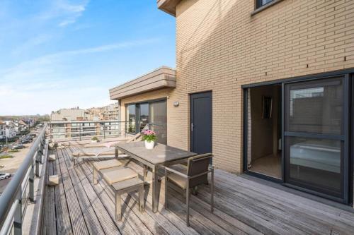 una terrazza in legno con tavolo e sedie su un edificio di Ruim appartement met heerlijk zonneterras a Bruges