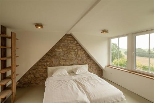 a bed in a room with a stone wall at Strumpffabrik in Kerpen