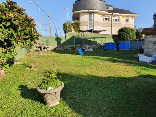 a yard with a house and a pot with flowers at Precioso chalet cerca de la playa de Samil in Vigo