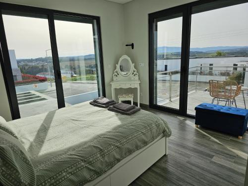 a bedroom with a bed and a fireplace and large windows at Villa Joia in Bombarral