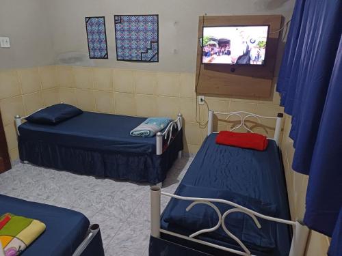 a room with two beds and a tv in it at Pousada Mara Mar Niterói in Niterói