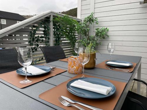 uma mesa com pratos e copos de vinho numa varanda em Moderne rekkehus, god standard. em Ålesund
