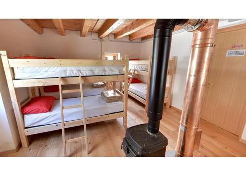 a room with two bunk beds and a wood stove at Rifugio Alpe Bonze in Donnas